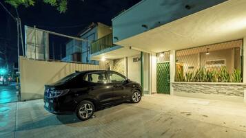 A modern house with a car parked in the driveway, a gated entrance, and a balcony.