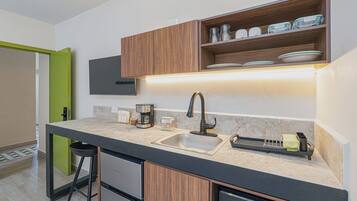 A modern kitchen with a built-in sink, a coffee maker, and a dish rack.