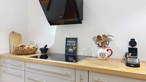 A kitchen with a modern stove, a coffee maker, a basket of fruit, and a cookbook. - Wonderful private villa for 6 guests with WIFI and patio (Bärental)