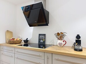 Eine Küche mit modernem Herd, einer Kaffeemaschine, einer Obstschale und einem Kochbuch.