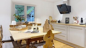 A modern kitchen with a wooden dining table, white cabinets, and a window with a view of greenery. - Wonderful private villa for 6 guests with WIFI and patio (Bärental)