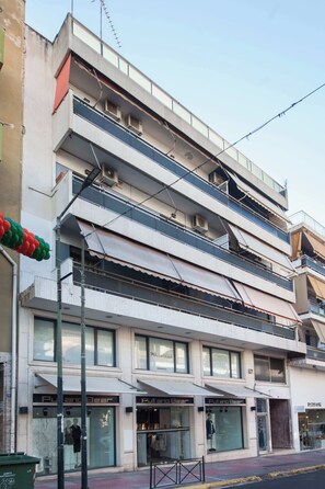 A multi-story building with storefronts on the ground floor, including a clothing store named 'Pull and Bear.' - Elegant 2 Bd Apt with Balcony in Korydallos Square (Koridallos)