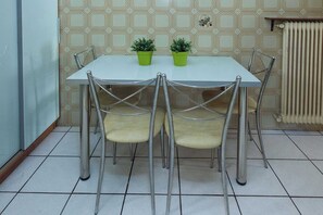 A dining table with four chairs, two potted plants, and a radiator in the background. - Elegant 2 Bd Apt with Balcony in Korydallos Square (Koridallos)