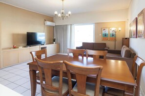 A dining area with a table and chairs, a television, and a sofa. - Elegant 2 Bd Apt with Balcony in Korydallos Square (Koridallos)