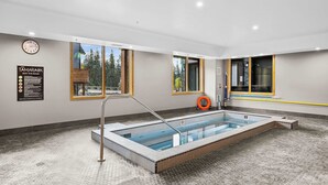 A swimming pool with a tiled floor, a clock, and a sign about hot tub rules. - BergTraum Refined Alpine Escape in Spring Creek (Canmore)