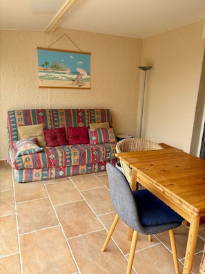 Ein gemütliches Zimmer mit einer gemusterten Couch, einem Holzesstisch und einem Stuhl.
