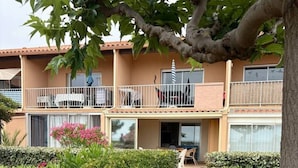 Un edificio de dos pisos con balcones, un sendero pavimentado y setos bien cuidados.