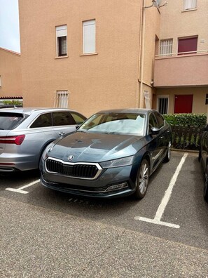 Ein Parkplatz mit einem dunkel gefärbten Auto in einer Parkbox.