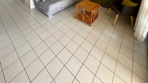 Una sala de estar con un sofá, una pequeña mesa de madera, un armario verde y una puerta.