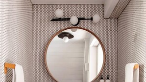 Un baño con un espejo redondo, encimera negra y paredes con diseño.