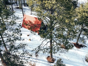 A red-roofed building surrounded by snow-covered ground and pine trees. - Cool A-Frame Cabin Rental in New Mexico, for Unforgettable Vacations on the Pecos River (Pecos)