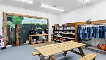 A room with a wooden table, shelves with various items, and a wall mural.