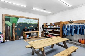 Une pièce avec une table en bois, des étagères remplies de divers objets et une fresque murale.