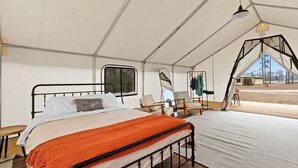 A tented accommodation with a bed, chairs, and a view of the outdoors. - Outdoor Adventure Basecamp: World-Class Fishing, Hiking Trail & Pet-Friendly Fun in Wewahitchka, Florida (Wewahitchka)