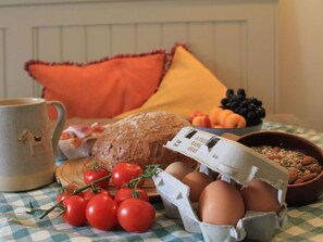 Une table mise pour le petit-déjeuner avec du pain, des œufs, des tomates, un saladier de fruits et une tasse.