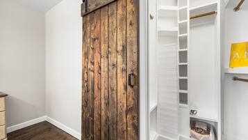 Una habitación con puerta corrediza de madera, paredes blancas y un armario blanco con estantes.