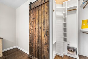 A room with a wooden sliding door, white walls, and a white closet with shelves. - 3br in Crestwood minutes from Downtown (Birmingham)