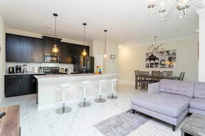A modern kitchen with dark cabinets, a white island with bar stools, and pendant lighting. - 1144 CD - CHAMPIONS GATE (Kissimmee)