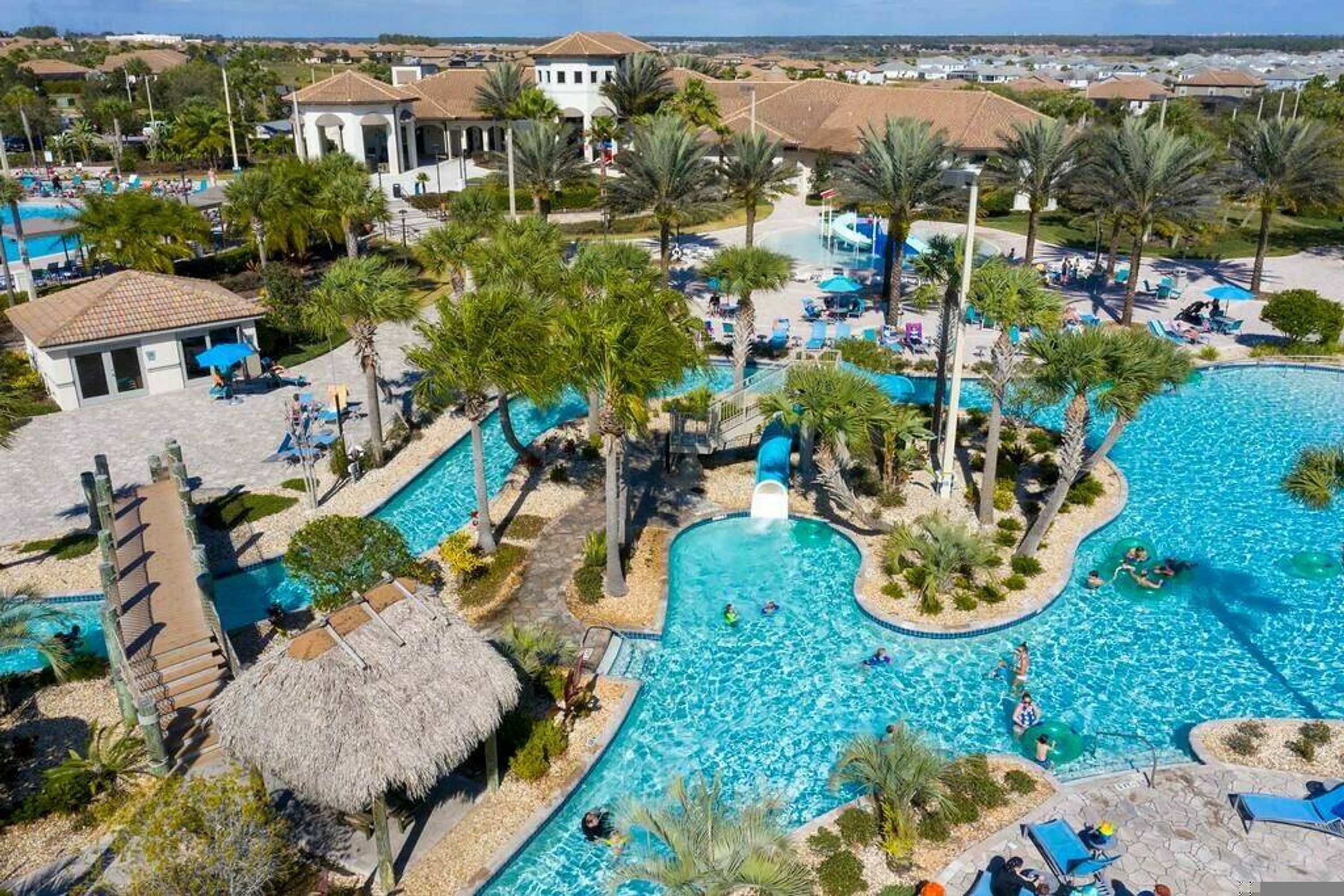 A resort with multiple swimming pools, palm trees, and lounge areas.