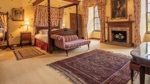 Un lit à baldaquin, une cheminée et un tableau accroché au mur.