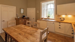 Une cuisine avec une table en bois, des placards blancs, une fenêtre et un évier.