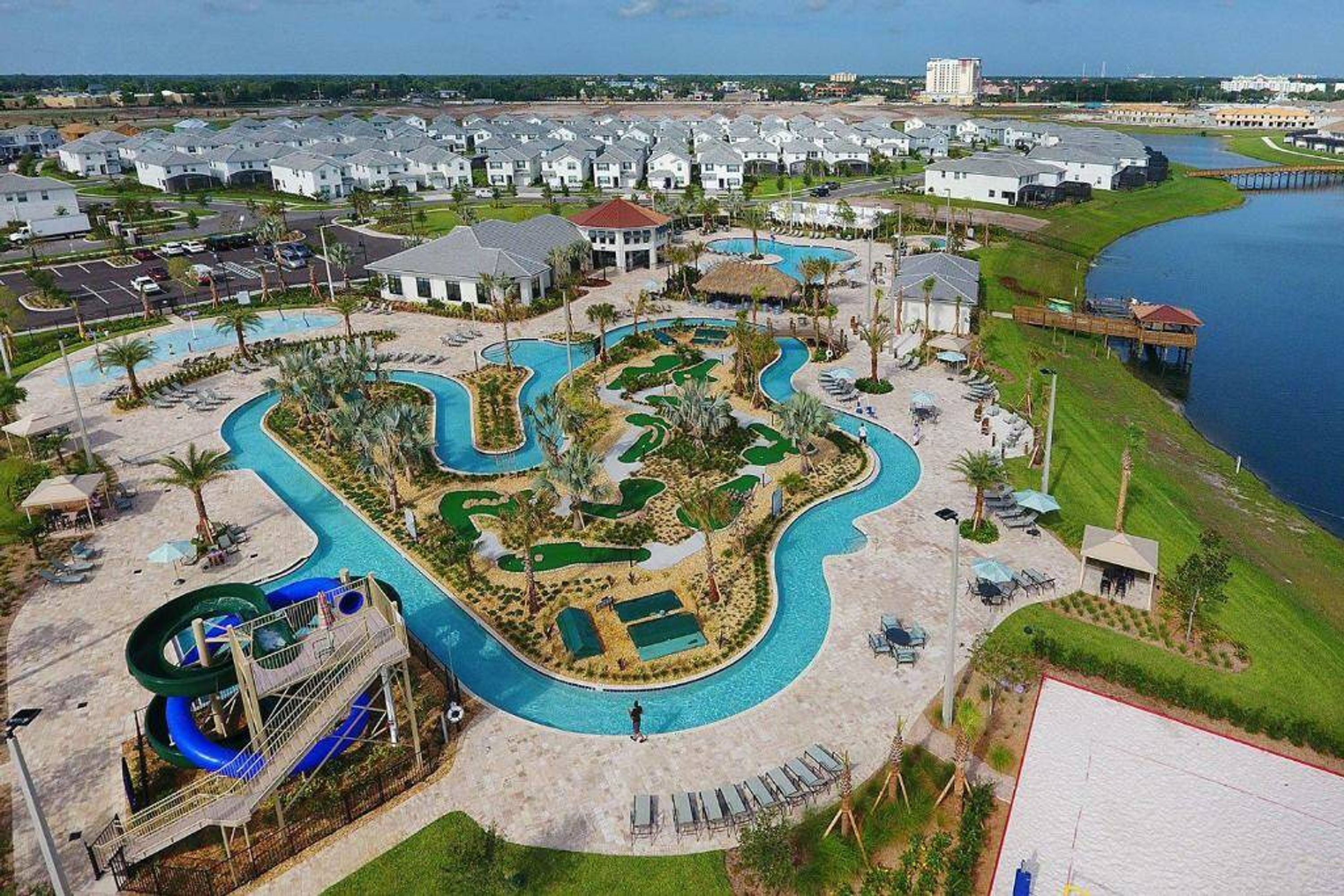 An aerial view of a resort with multiple swimming pools, a water slide, and a marina.