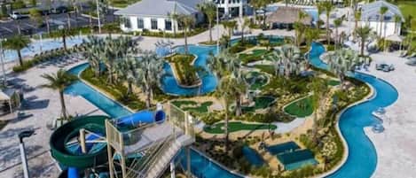 A resort with a swimming pool, palm trees, and a water slide.