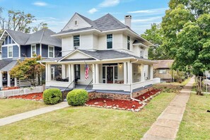 A two-story house with a porch, a flag, and a well-maintained lawn. - Newly renovated Magic on 17th! Min from Protective, UAB, BJCC. Sleeps 10 (Birmingham)