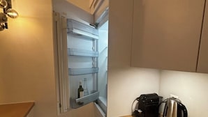 Una cocina compacta con refrigerador, hervidor y pileta.