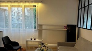 Una sala de estar con un sofá, dos sillones, una mesa de centro de vidrio y un mueble para televisión.