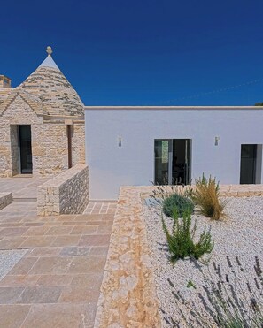 A modern building with a stone structure and a white facade, featuring a stone staircase and a gravel area with plants. - Trullo with infinity pool amid olive groves (Alberobello)