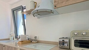 A kitchen with wooden cabinets, a built-in oven, a toaster, and a window. - Trullo with infinity pool amid olive groves (Alberobello)