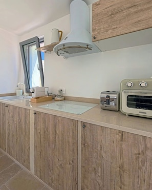 Eine Küche mit Holzausstattung, einem Backofen, einem Toaster und einem Fenster.
