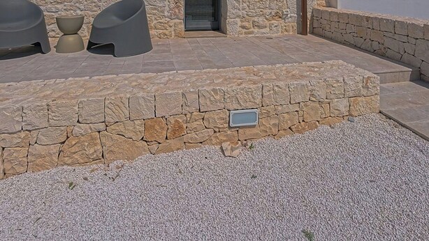A stone building with a conical roof, a door, and a small outdoor seating area with two chairs and a table. - Trullo with infinity pool amid olive groves (Alberobello)