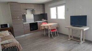 Eine kleine Küche mit Essbereich, einem Fernseher und einem Fenster.