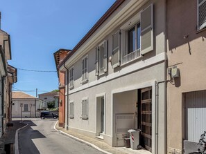 A narrow street with buildings, a parked car, and a bicycle. - Casa Nuvola (Senigallia)