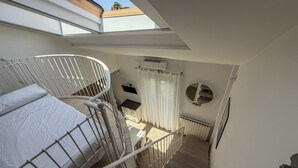 A bedroom with a bunk bed, a skylight, a round mirror, and a view of the outside. - Casa Nuvola (Senigallia)