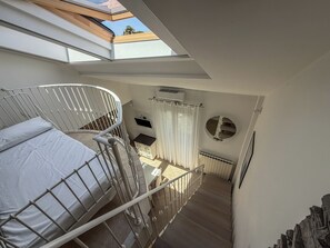 A bedroom with a bunk bed, a skylight, a round mirror, and a view of the outside. - Casa Nuvola (Senigallia)