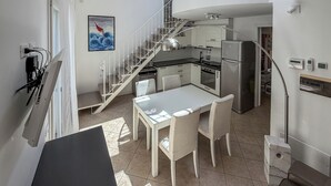 A modern kitchen with a dining area, a staircase, and a view of the outside. - Casa Nuvola (Senigallia)