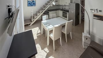 Cozinha moderna com área de refeições, escada e vista para o exterior.