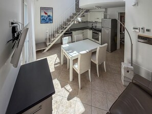 A modern kitchen with a dining area, a staircase, and a view of the outside. - Casa Nuvola (Senigallia)