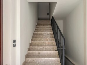 A staircase with a handrail, leading to a landing with a light switch. - Casa Nuvola (Senigallia)