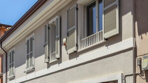A building facade with multiple windows, shutters, and a visible air conditioning unit. - Casa Nuvola (Senigallia)