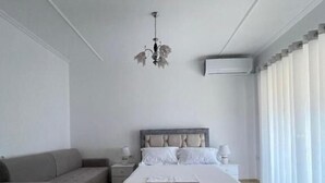 A modern bedroom with a large bed, a sofa, a nightstand, and a chandelier. - SeaSide Apartments (Sarande)