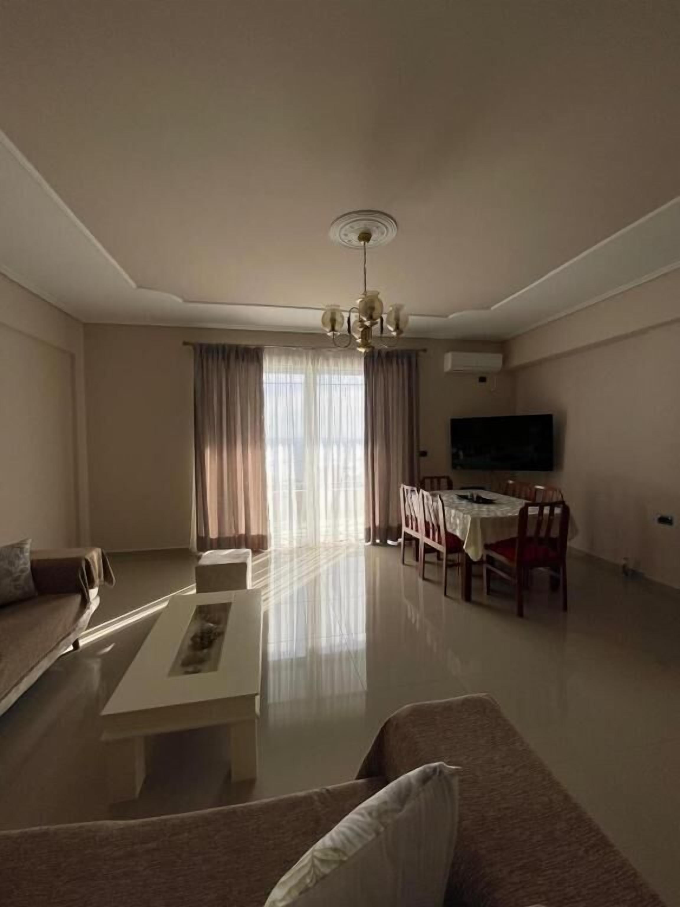 Una sala de estar con sofá, mesa de centro, mesa de comedor, sillas y televisor.