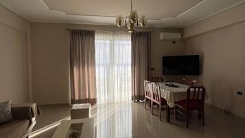 Una sala de estar con sofá, mesa de centro, mesa de comedor, sillas y televisor.