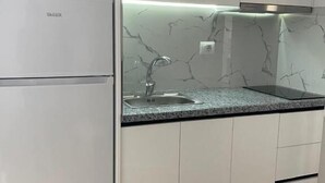 A kitchen with white cabinets, a marble backsplash, and a built-in refrigerator. - SeaSide Apartments (Sarande)