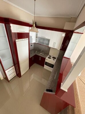 A compact kitchen with white cabinets, a built-in oven, and a countertop. - SeaSide Apartments (Sarande)