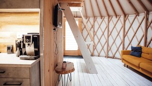 A cozy interior with a wooden ceiling, a sofa, a coffee machine, and a small table.