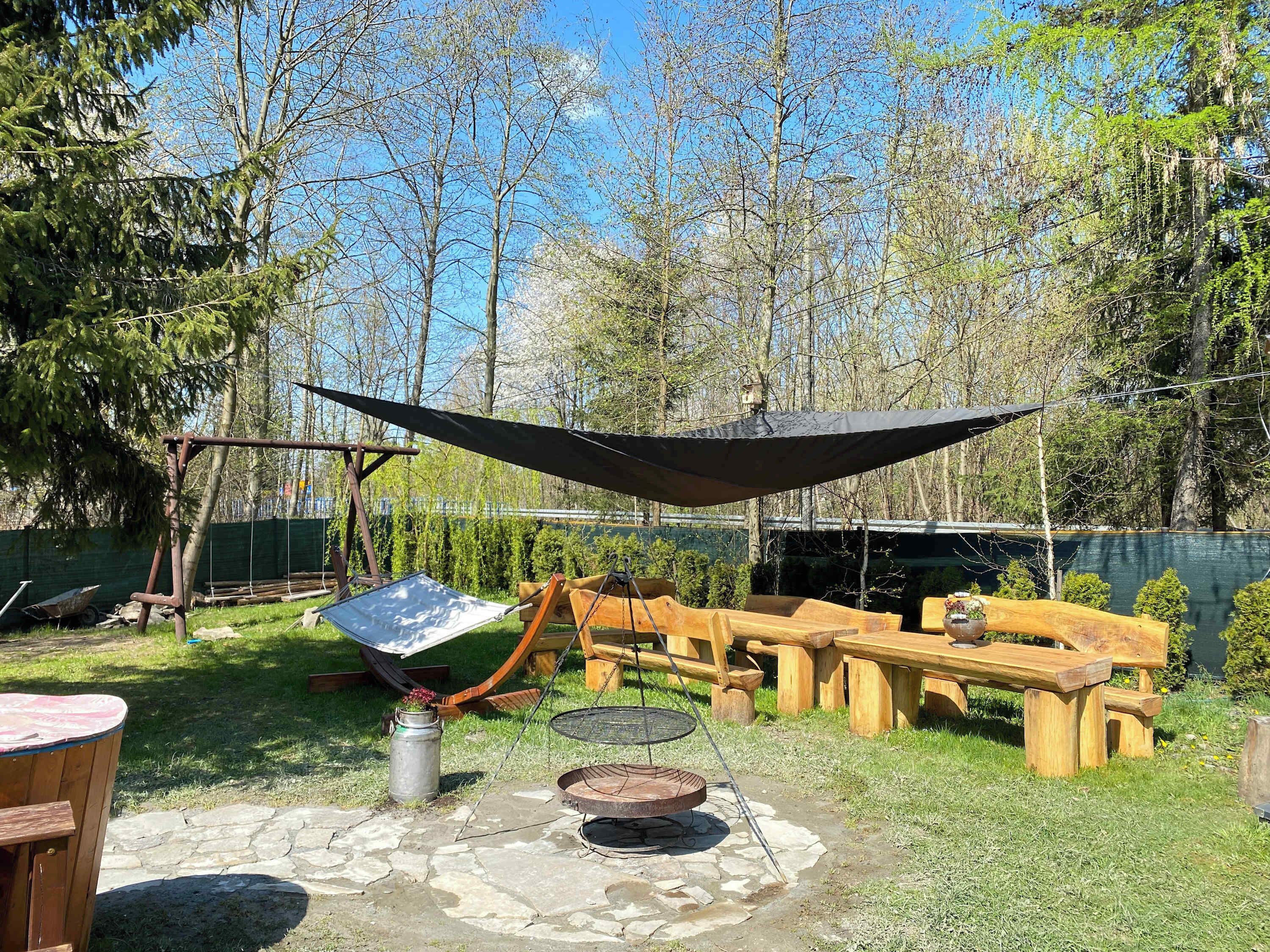 Eine Holzterrasse mit Grilltisch, einer Hängematte und einem Picknicktisch.